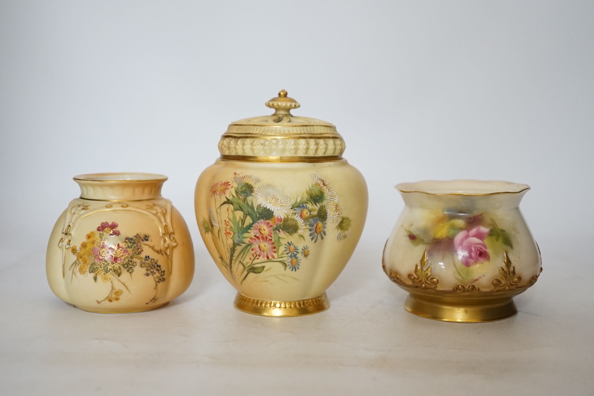 Three Royal Worcester blush ivory pots, one with an inner lid and pierced outer lid, tallest 14cm